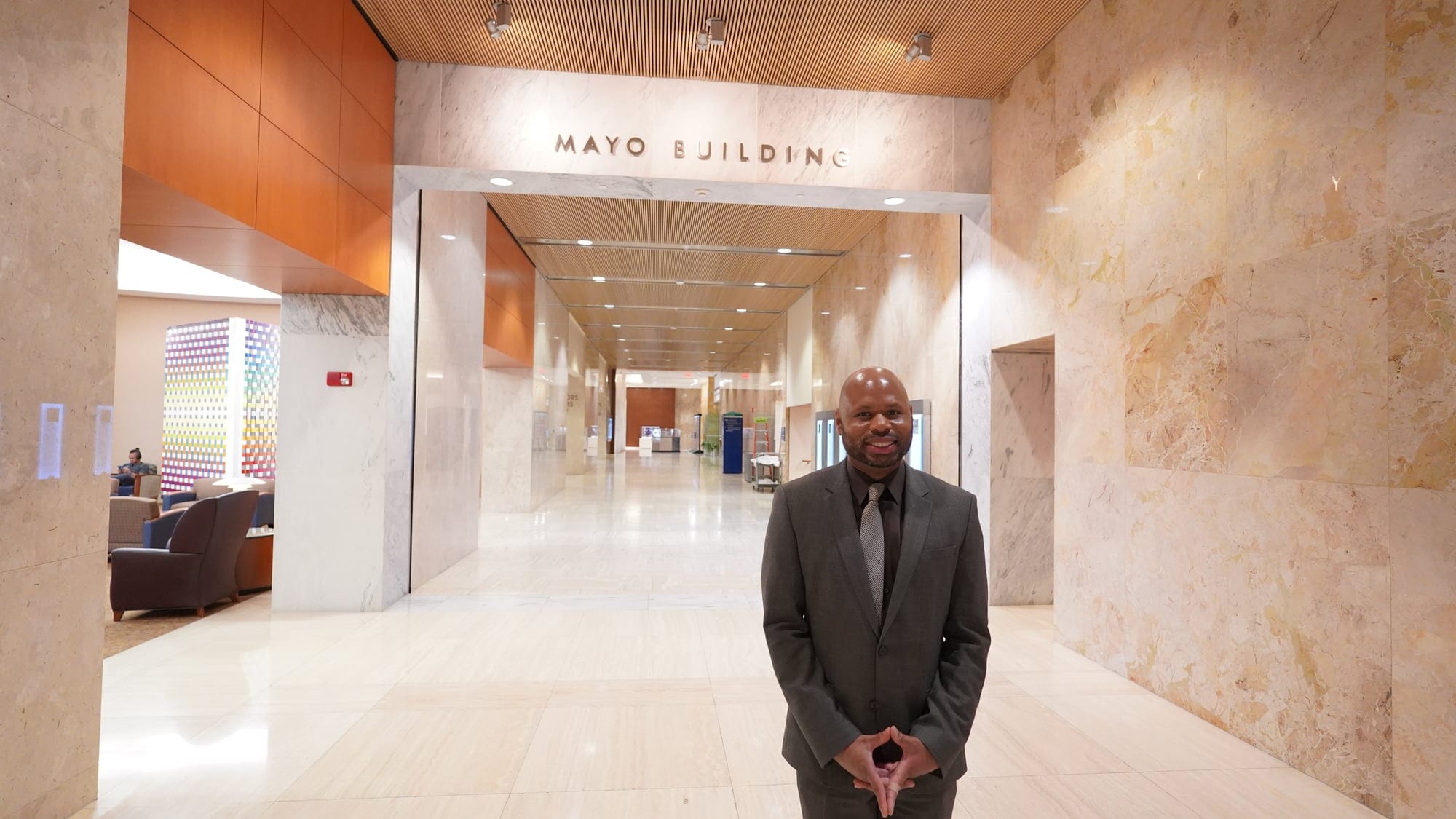 Dante King standing alone in an institutional corridor, in a suit.